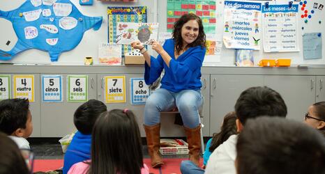 A teacher reads a story to her class of young students. 