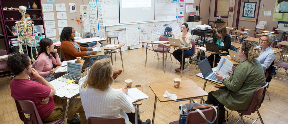 Teachers sitting in a circle in desks discussing a problem